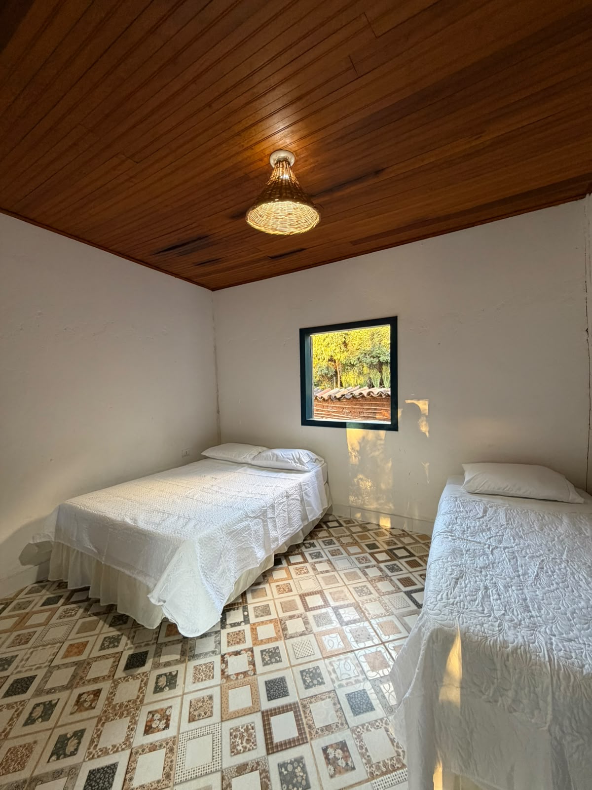 Quarto com piso ladrilhado e luminária de fibra natural