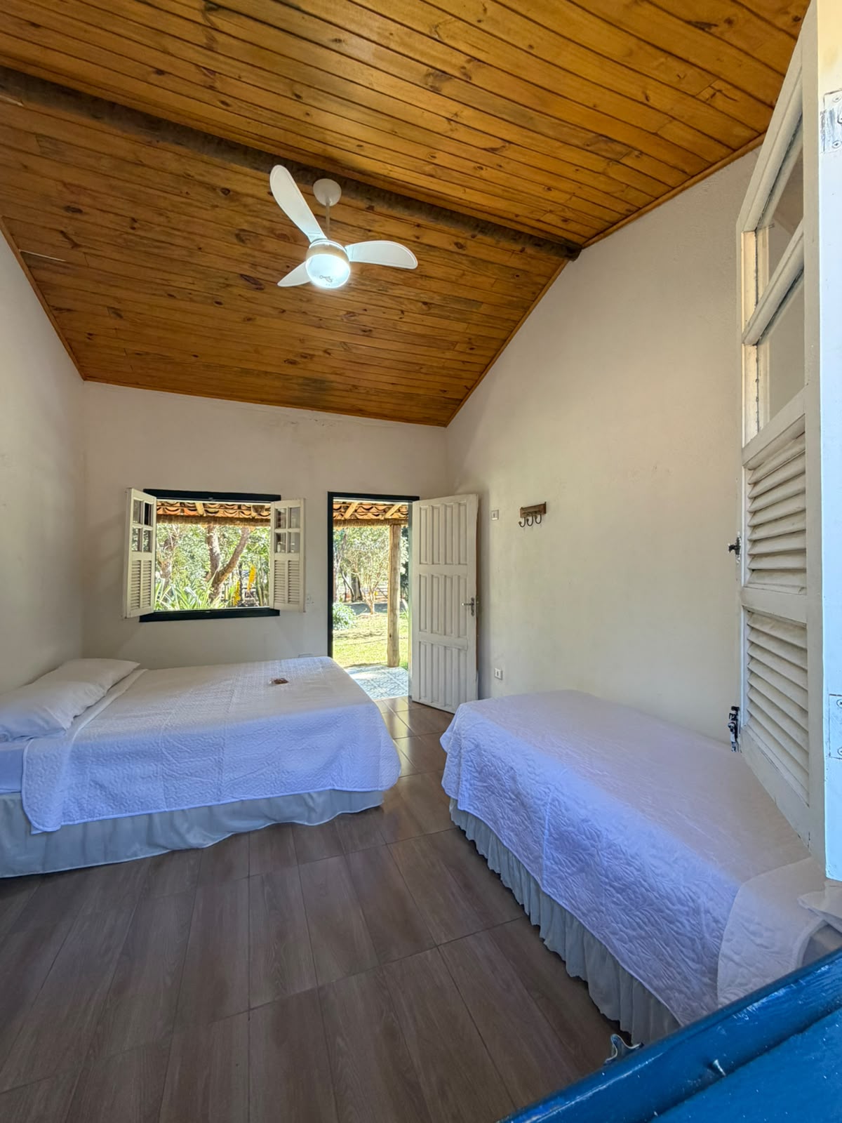 Quarto com ventilador de teto e acesso à varanda