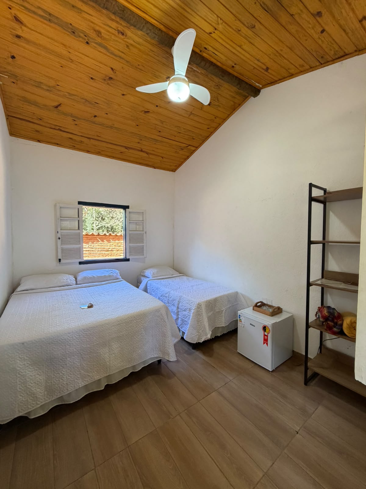 Quarto com frigobar e estante de madeira